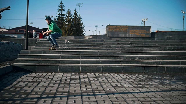 一个年轻人在阳光明媚的城市里玩滑板跳楼梯视频素材