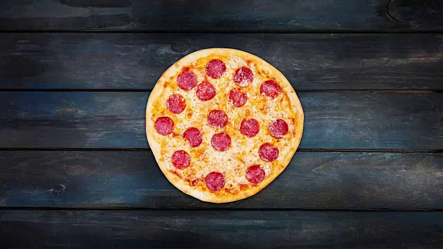 在深色木质背景上旋转经典的意大利辣香肠披萨。俯视图中心方向视频素材
