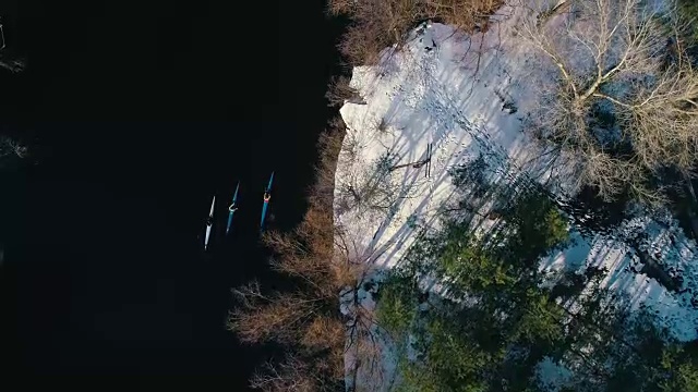 4 k空中镜头。俯视图三个皮划艇在河流在春天附近海岸桥下视频素材
