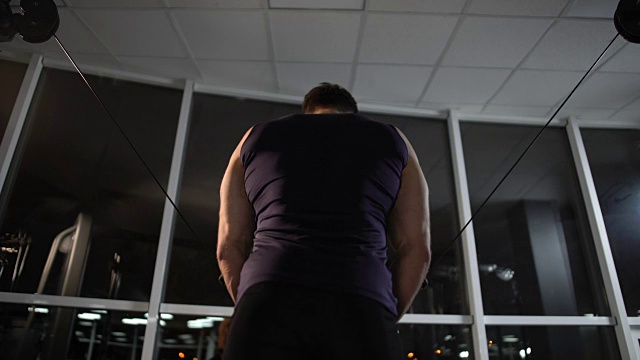 坚持不懈的运动员，即使在很晚的时间，仍在拉索机上锻炼胸部肌肉视频下载