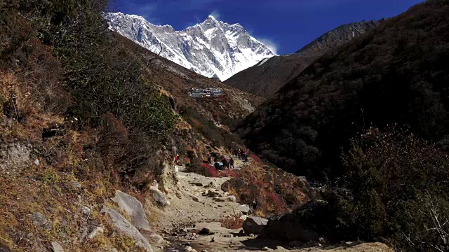一群游客和搬运工在喜马拉雅山的小路上。慢动作镜头。4 k, UHD视频素材