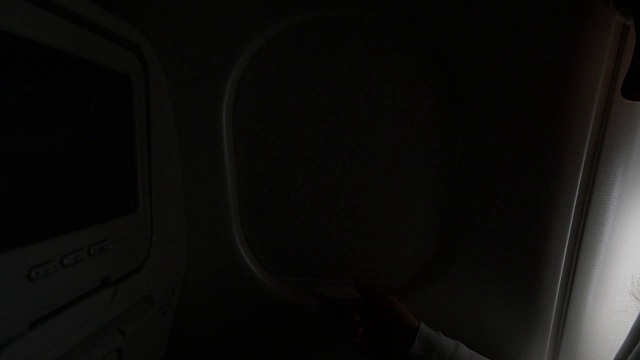 特写:女子打开飞机窗户，让眩目的光线进入机舱视频素材