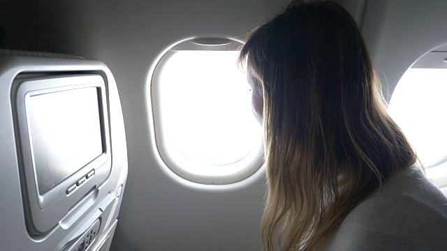 近距离观察:年轻女子透过飞机的窗户，关上百叶窗。视频素材