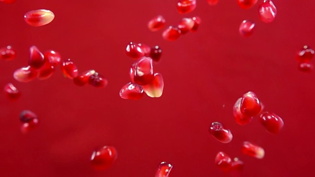 成熟的红石榴子在红色的背景上飞舞视频素材