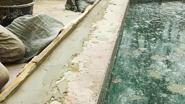 施工现场的抹刀、铲斗和灰浆。建筑工用灰泥粉刷表面。4 k。池修理。视频下载