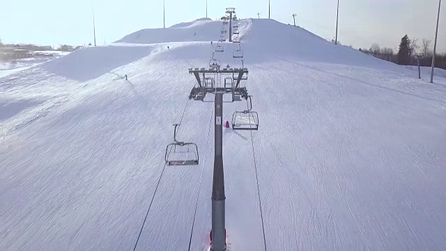 滑雪电梯，用于在滑雪胜地的雪山上运输滑雪者和滑雪板。滑雪缆车与椅子在雪坡无人机视图视频素材