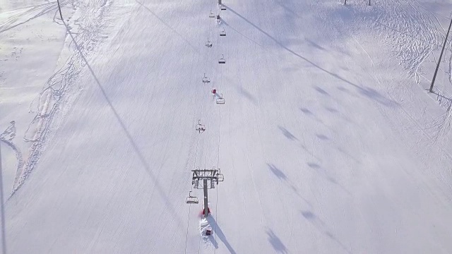 人们在冬季滑雪场的雪坡上滑雪和滑板。滑雪电梯在雪山无人机视图。滑雪胜地冬季活动鸟瞰图视频素材