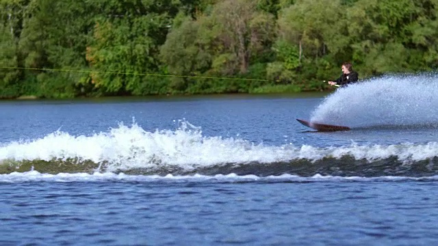 年轻人冲在水里，在摩托艇后面坐着水。极端的水上运动视频素材