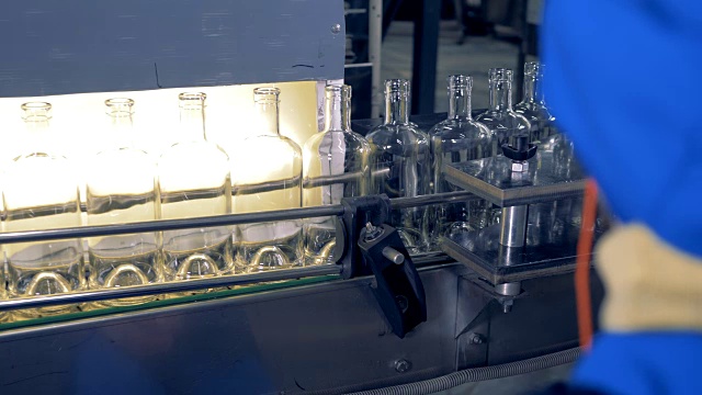 空瓶子在生产线上，一名工厂工人在观察这项技术。4 k。视频素材