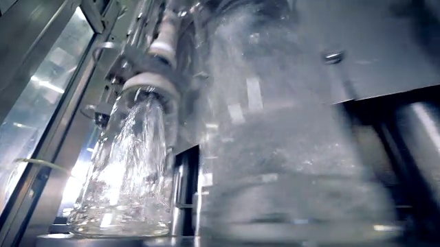 当机器往瓶子里装酒精时，瓶子会四处移动。4 k。视频素材