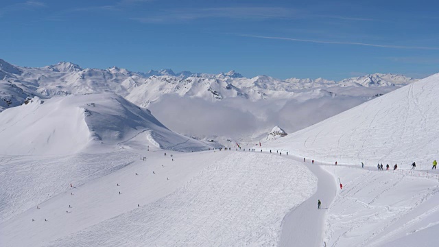 阳光明媚的一天在雪山滑雪场，许多滑雪者在斜坡上视频素材