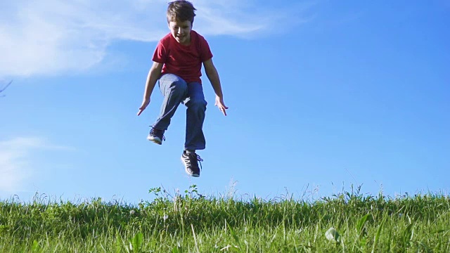 快乐的男孩在绿色的草山上跳跃视频素材