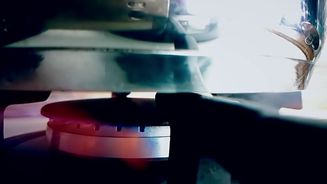 炉顶燃烧器点燃成蓝色烹饪火焰与锅在顶部的慢动作，在厨房的特写视图视频素材
