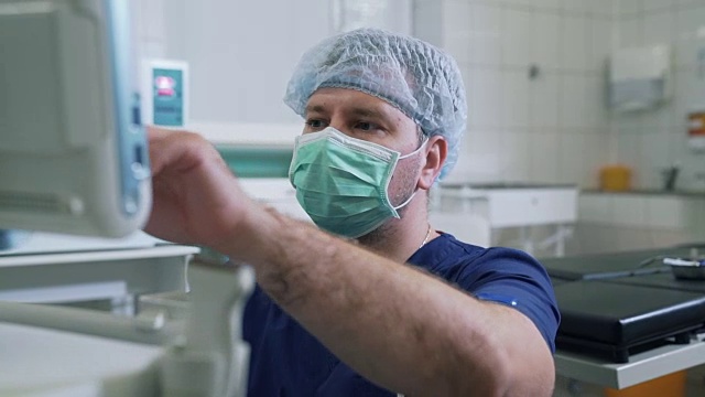 医生在医院里穿着无菌的衣服，戴着口罩和诊断设备一起工作。超声波检查装置监测。诊所的医疗工具视频下载