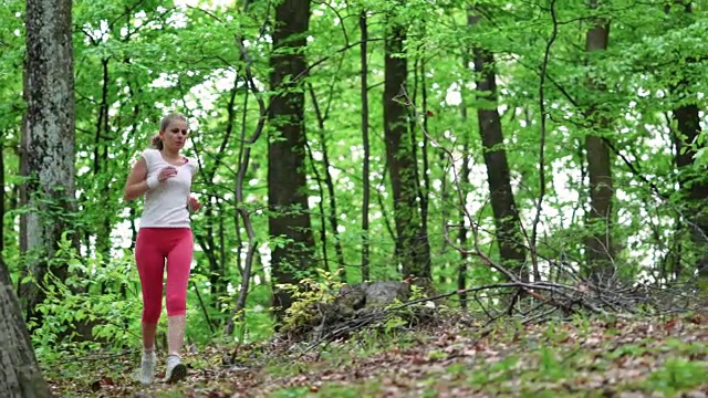 在大自然中奔跑后，年轻的女运动员在树桩上休息。视频素材