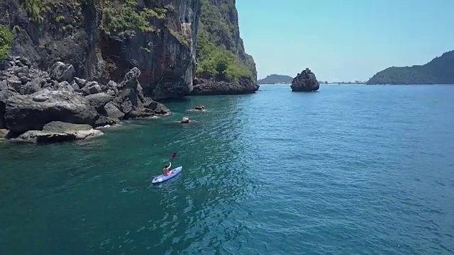 空中飞行，在年轻的女游客身后划着桨经过巨大的石灰岩悬崖视频下载