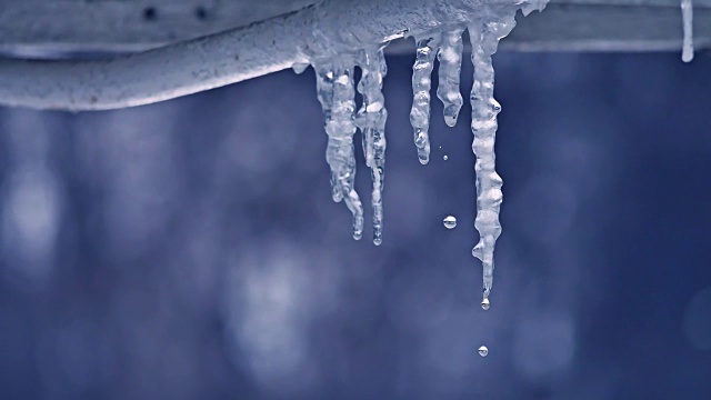 融化的冰柱和水滴靠近。冬天是室外冰柱滴下的最后一滴水视频下载