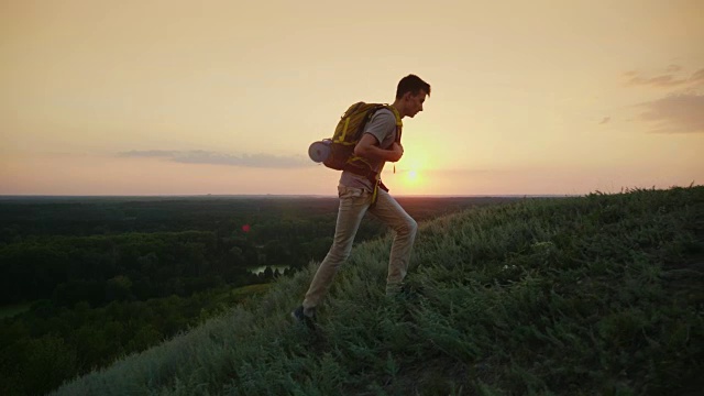 那个背着背包的少年爬上了山。在日落时分。从青年开始积极的生活方式视频购买