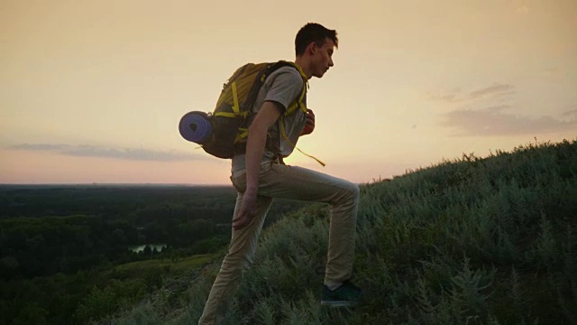 一个疲惫的少年爬上了山。日落时分，背着一个背包视频素材