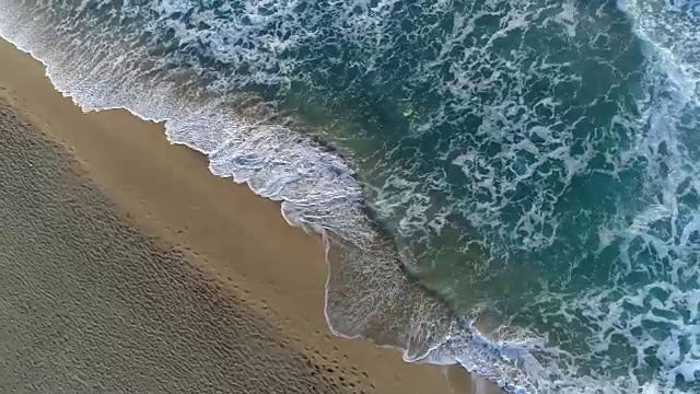 飞过空荡荡的沙滩和海浪。鸟瞰图视频素材