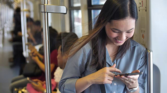 年轻漂亮的女人在公共交通工具上使用智能手机视频素材
