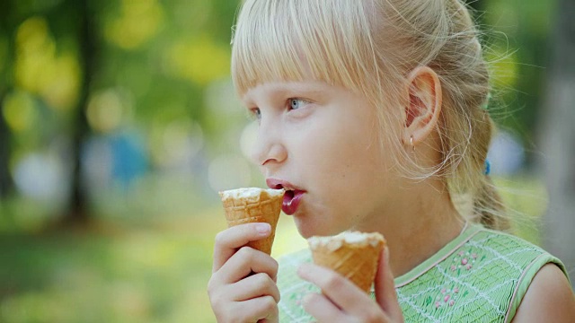 女孩同时吃了两筒美味的冰淇淋。暑假，在公园里休息视频下载