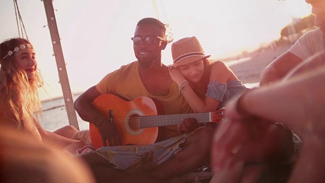 年轻的多民族潮人在海滩派对上听原声吉他视频素材