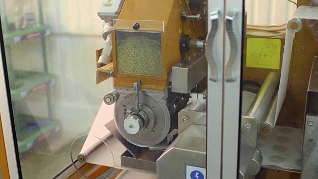 制作茶包的工人在机器内部调整纸带和转动阀门视频下载