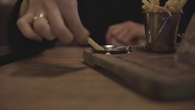 女性手蘸酱薯条的特写。视频下载