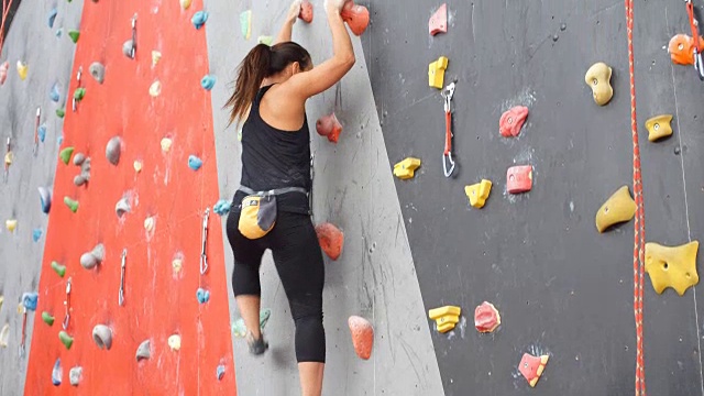 妇女在室内的人造墙上练习攀岩。积极的生活方式和抱石理念视频素材