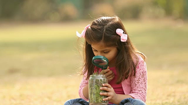 印度德里花园，一个女孩拿着放大镜在罐子里看视频素材