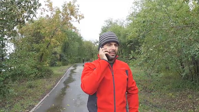 男人在秋天的城市公园打电话。视频素材