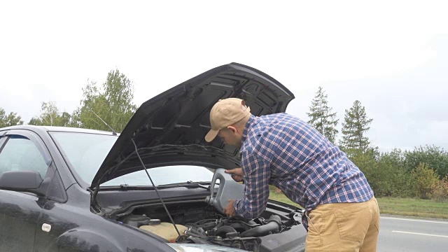 汽车维修技师将新的润滑油注入汽车发动机。路边的司机给发动机注机油。视频下载