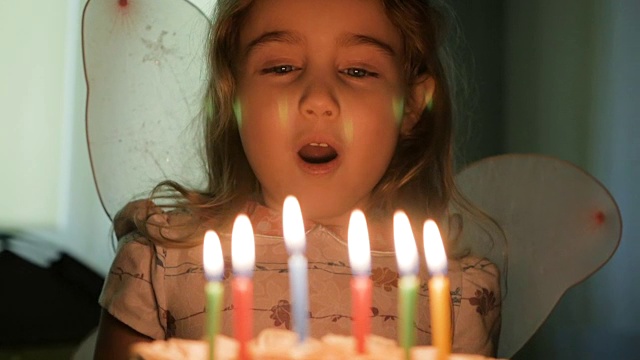 小女孩吹灭生日蛋糕上的蜡烛。特写镜头。缓慢的运动。视频素材