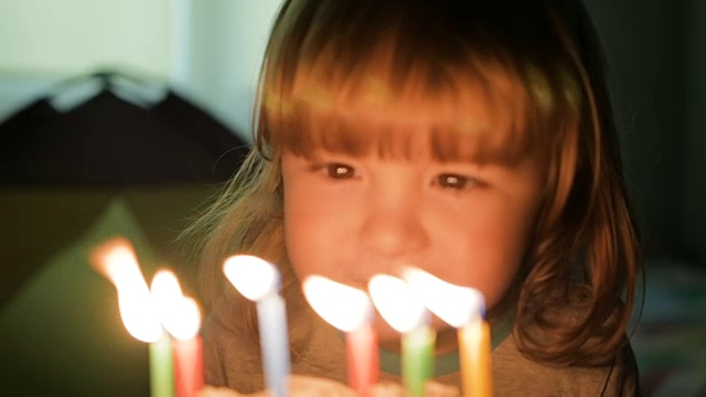 小男孩吹灭生日蛋糕上的蜡烛。特写镜头。缓慢的运动。视频素材