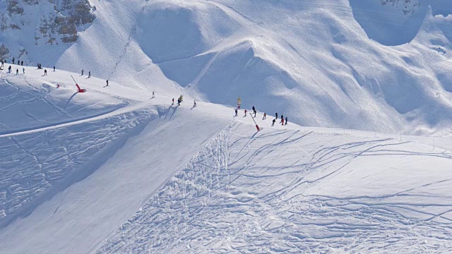阳光明媚的一天在雪山滑雪场，许多滑雪者在斜坡上视频素材