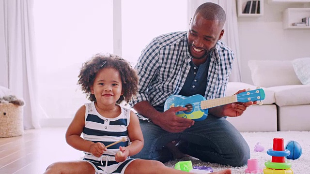 年轻的黑人爸爸和他年轻的女儿在演奏乐器视频素材