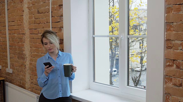 在阁楼现代办公室里用智能手机喝咖啡的美女视频素材
