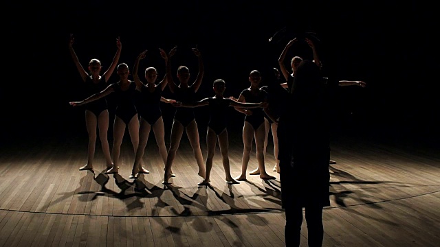 编舞在黑暗中教孩子们跳芭蕾。视频素材