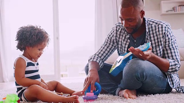 年轻的黑人爸爸和他年轻的女儿在演奏乐器视频素材