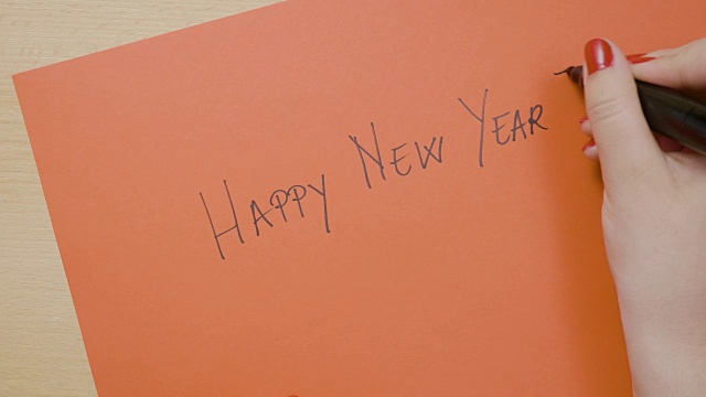 年轻女性用黑色记号笔在红纸上写下新年快乐视频下载