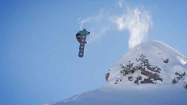 滑雪板从悬崖上跳下来，在半空中旋转，在刚落下的雪上着陆视频素材