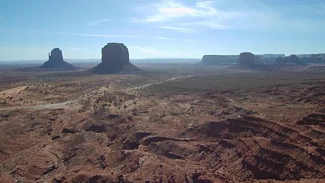 一架无人机飞过亚利桑那州奥尔加托纪念碑谷的一个山丘和平顶山岩层的沙漠视频素材