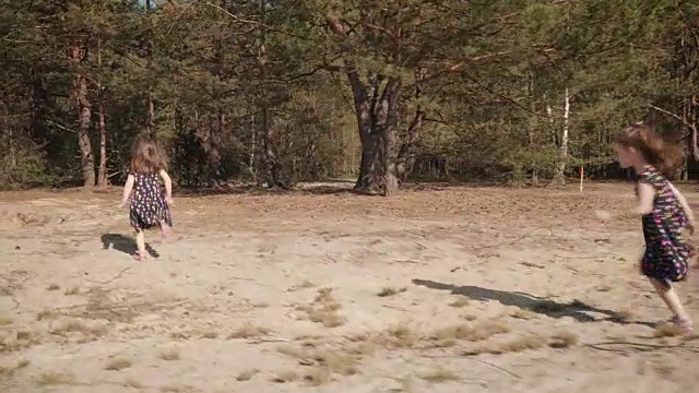 在夏日的森林里，两个女孩在沙地上奔跑视频素材