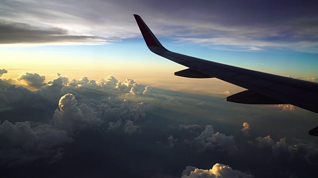 4K镜头的飞机在日落时飞过神奇的云和天空，旅行和交通的概念视频素材