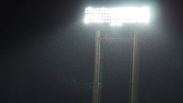 在一场大雨中，体育场的灯光在夜间闪烁，伴随着球迷的欢呼声视频素材