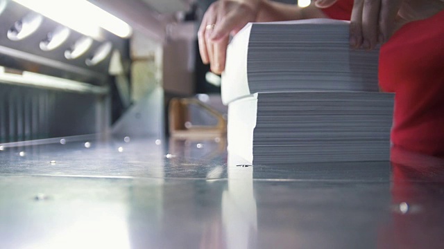 一名女工将一叠印刷字体的纸折叠起来视频素材