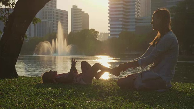 一家人在公园里玩，湖和摩天大楼为背景视频素材