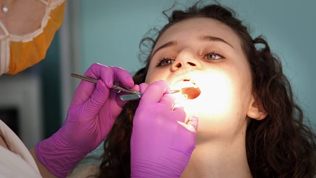 女牙医在她的病人的牙齿工作视频素材
