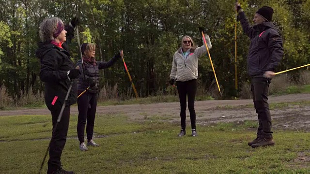 站在草地上，用北欧手杖做全身运动的老年人朋友视频素材